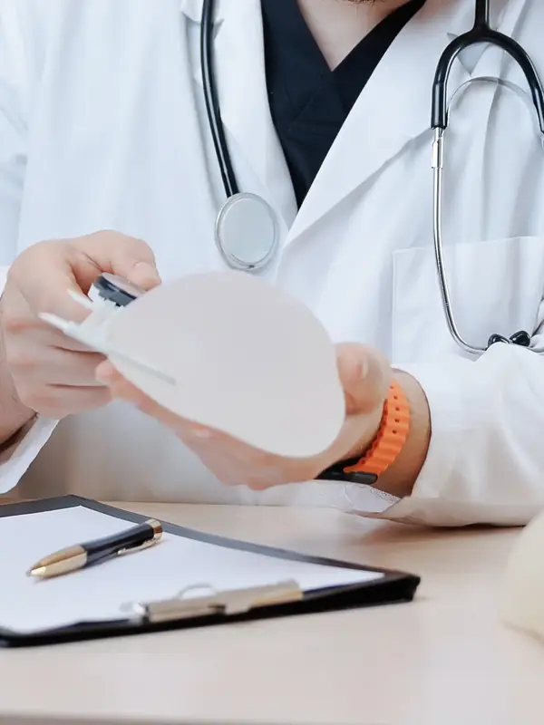 Doctor holding a breast implant at a consultation desk